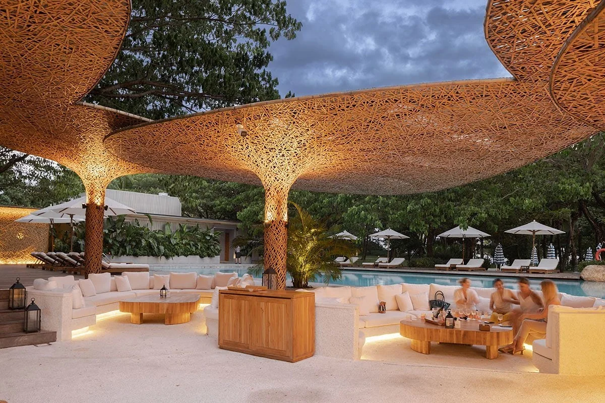 Illuminated woven bamboo canopy beside a resort pool